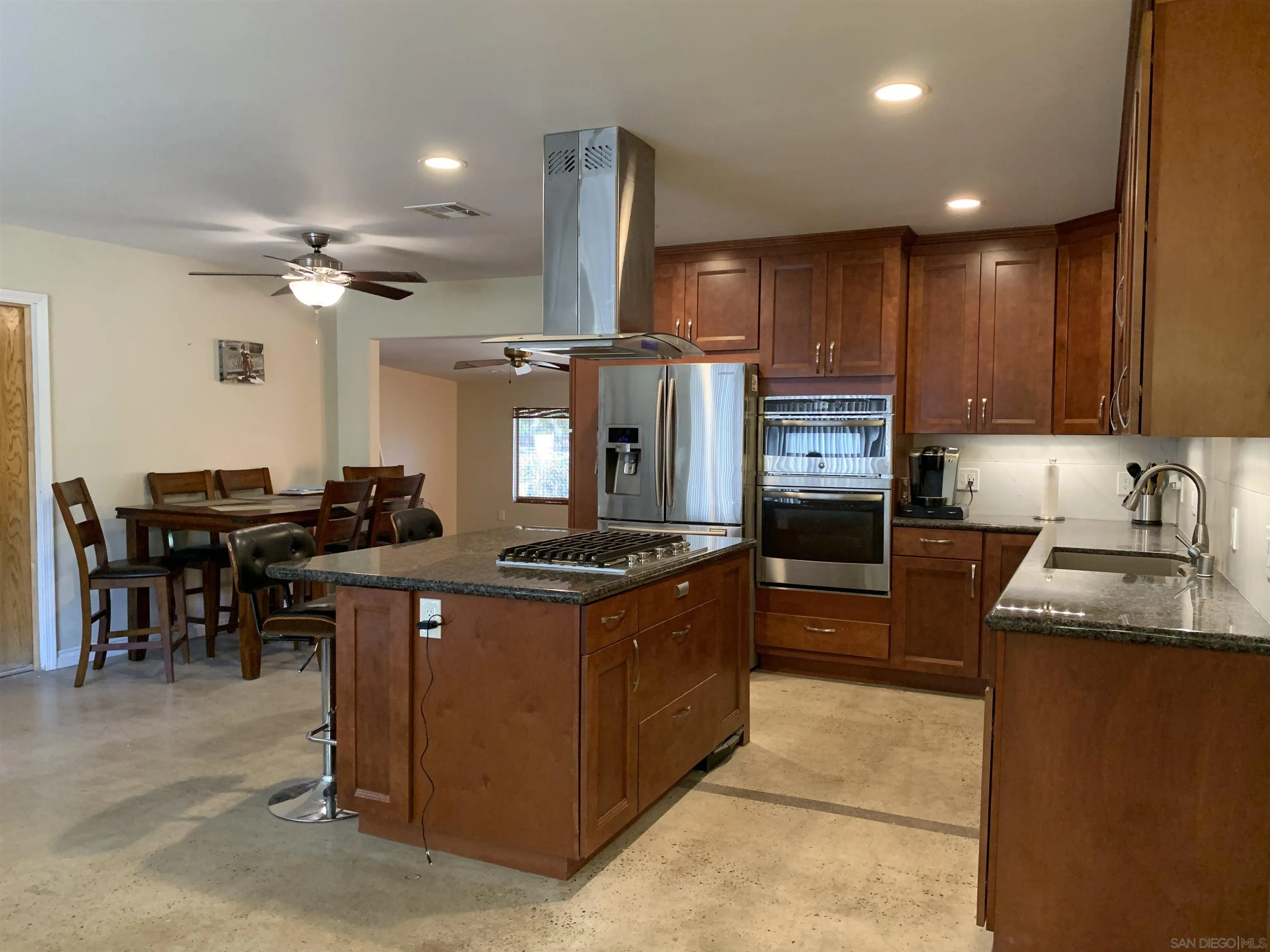 9935 Blossom Valley Road El Cajon, CA 92021 - Photo 7 of 36 a kitchen with kitchen island granite countertop a stove top oven a sink a dining table and chairs