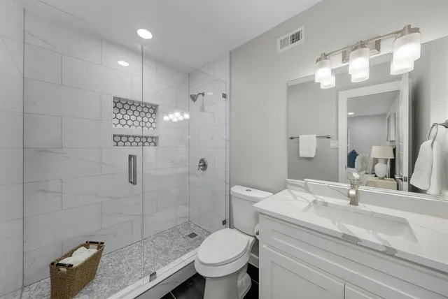 a bathroom with a granite countertop sink a toilet and shower
