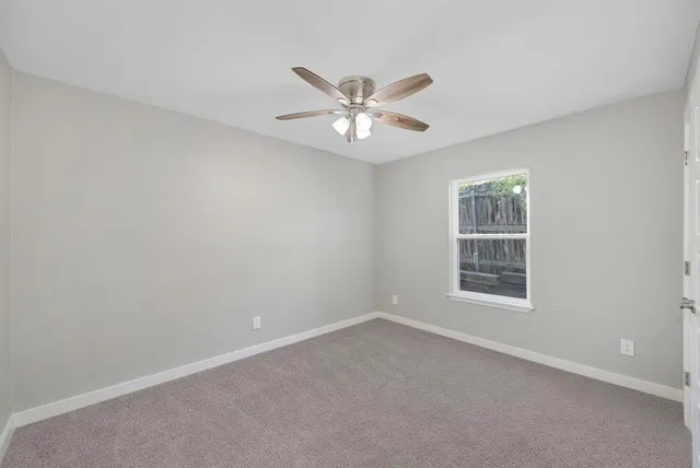 an empty room with window and ceiling fan