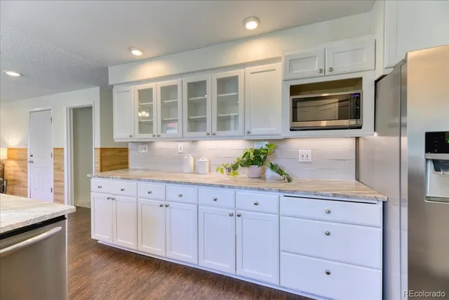 a kitchen with granite countertop white cabinets and stainless steel appliances