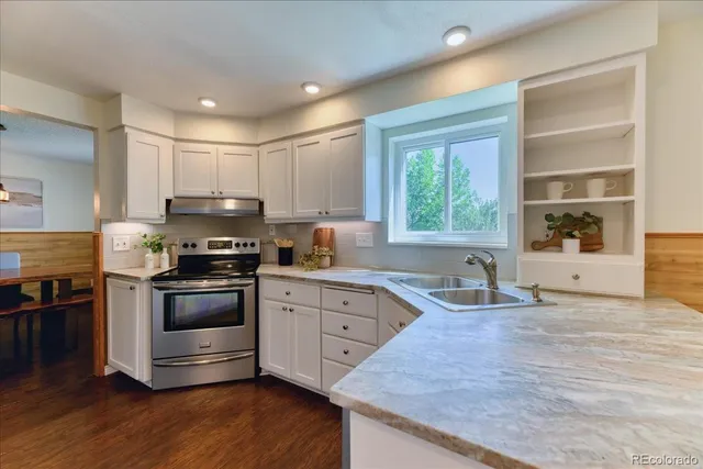 a kitchen with granite countertop a stove a sink and a microwave