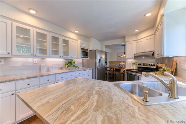 a large kitchen with kitchen island a large counter top stainless steel appliances and cabinets