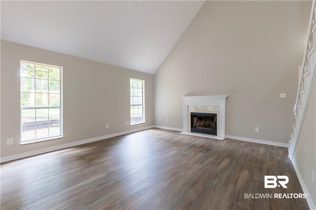 101 Lawson Road Daphne, AL 36526 - Photo 10 of 20 Spacious interior with vaulted ceilings, wood-finish flooring, a white mantel fireplace, and multiple grid-pattern windows