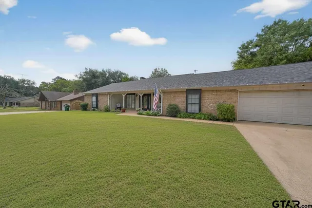 a front view of house with yard and trees in the background