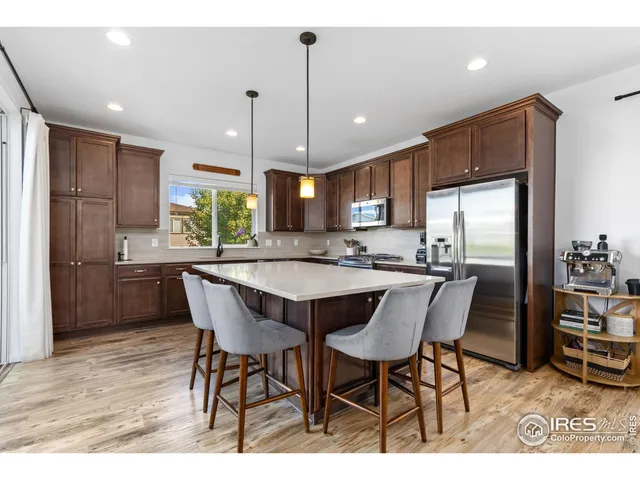 a kitchen with stainless steel appliances granite countertop a refrigerator a sink a stove a dining table and chairs