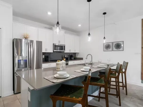 a kitchen with stainless steel appliances granite countertop a dining table chairs and white cabinets