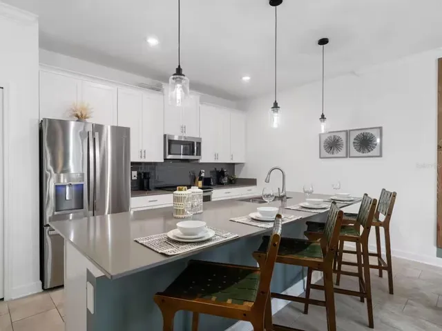 a kitchen with stainless steel appliances granite countertop a dining table chairs and white cabinets