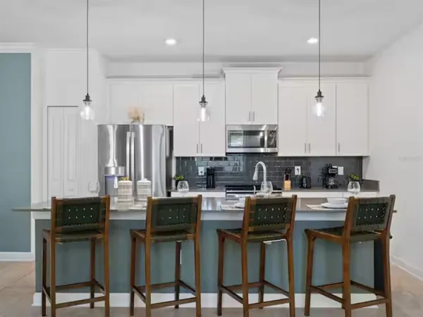 a kitchen with stainless steel appliances kitchen island granite countertop a table chairs stove and white cabinets