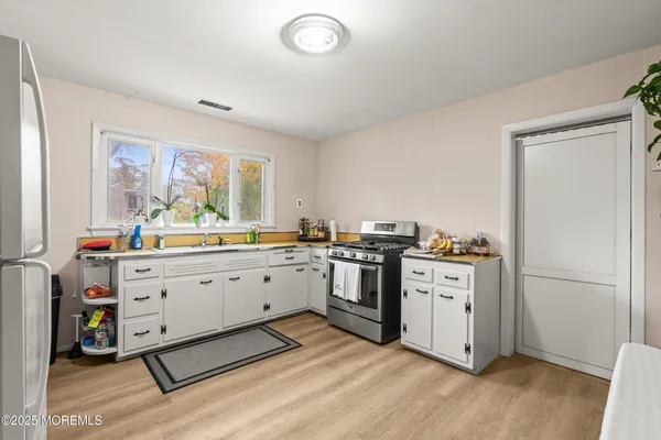 a kitchen with cabinets wooden floor and stainless steel appliances