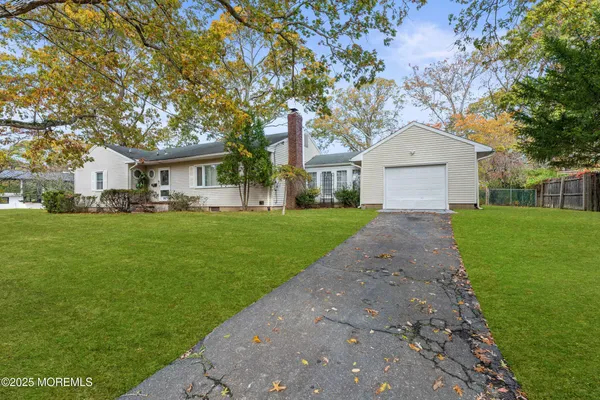 a front view of a house with a garden and trees