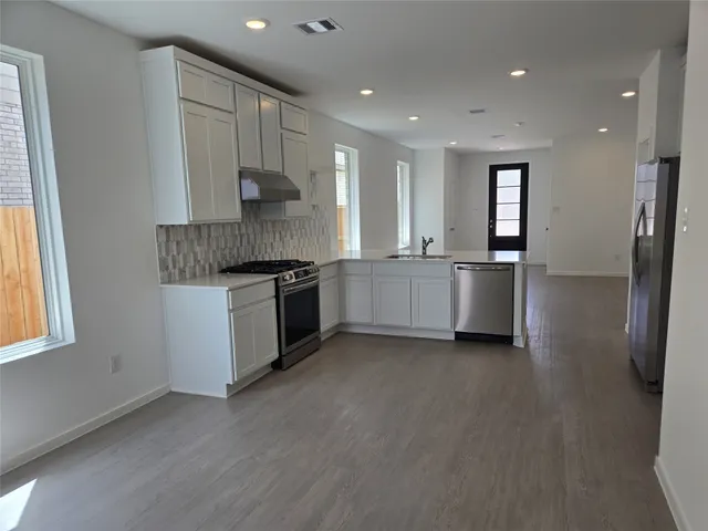 a kitchen with stainless steel appliances granite countertop a stove a sink and a refrigerator
