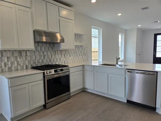 a kitchen with stainless steel appliances granite countertop a stove a sink and a refrigerator