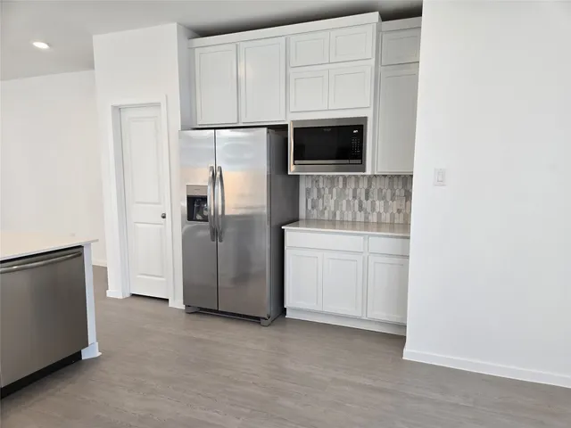 a kitchen with white cabinets and stainless steel appliances