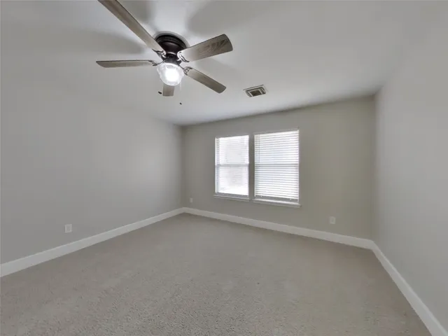 an empty room with a window and a fan