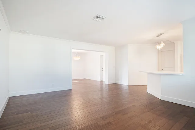 a view of an empty room with wooden floor and cabinets