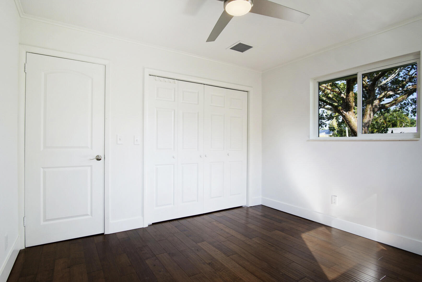 924 Pompano Drive Jupiter, FL 33458 - Photo 25 of 36 an empty room with wooden floor fan and windows