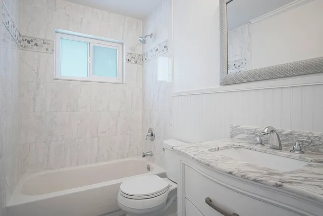 a bathroom with a granite countertop sink a toilet and shower