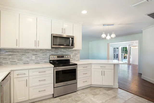 a kitchen with cabinets stainless steel appliances and wooden floor