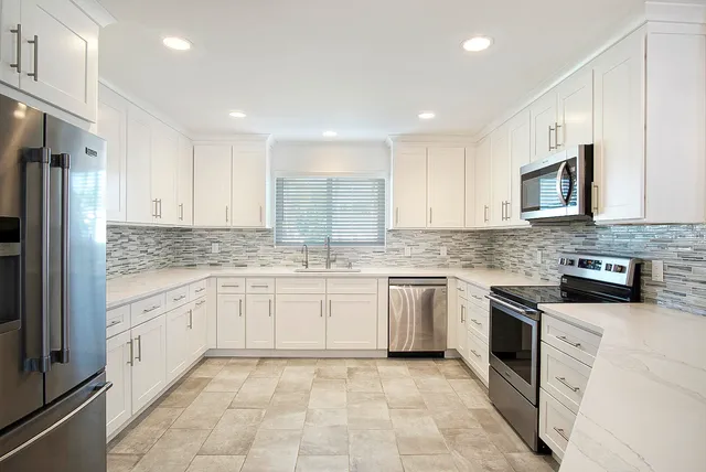 a kitchen with granite countertop white cabinets stainless steel appliances and a sink