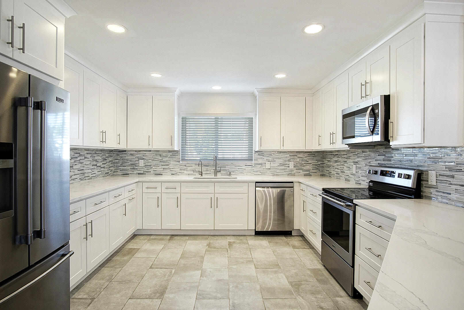 924 Pompano Drive Jupiter, FL 33458 - Photo 6 of 36 a kitchen with granite countertop white cabinets stainless steel appliances and a sink