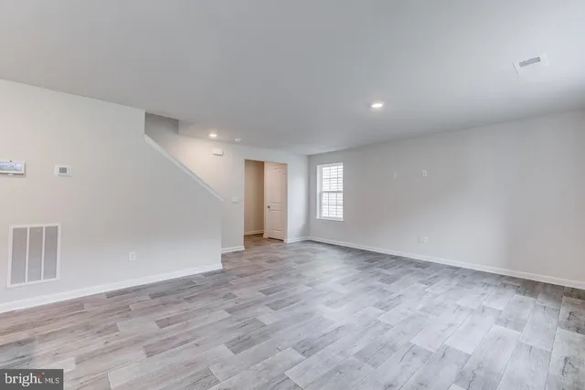 a view of an empty room with wooden floor and window