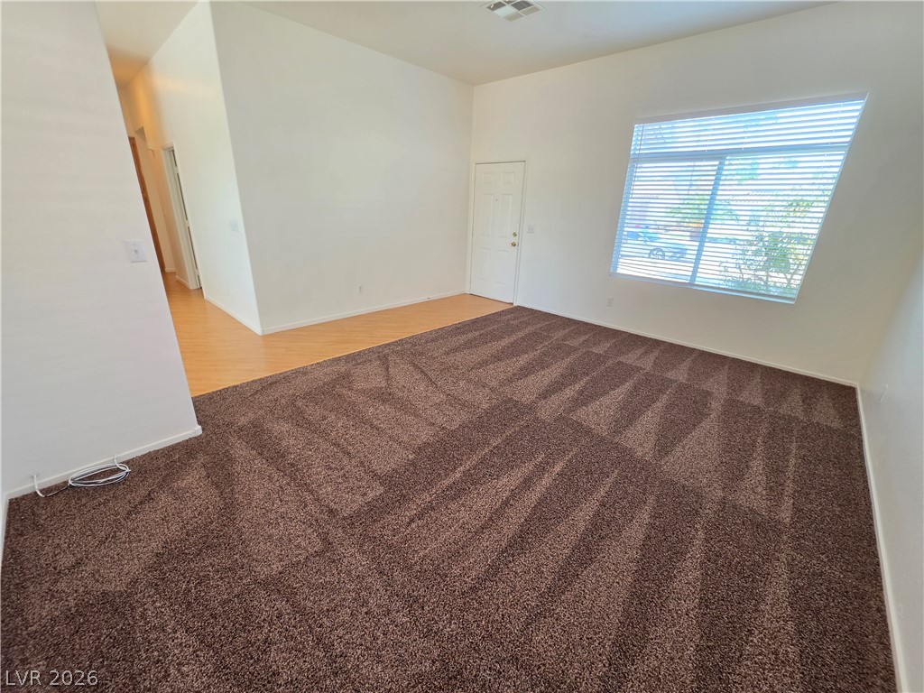 1154 Point Success Avenue Henderson, NV 89014 - Photo 9 of 26 A well-lit living area features warm brown carpeting and a natural wood floor entrance.