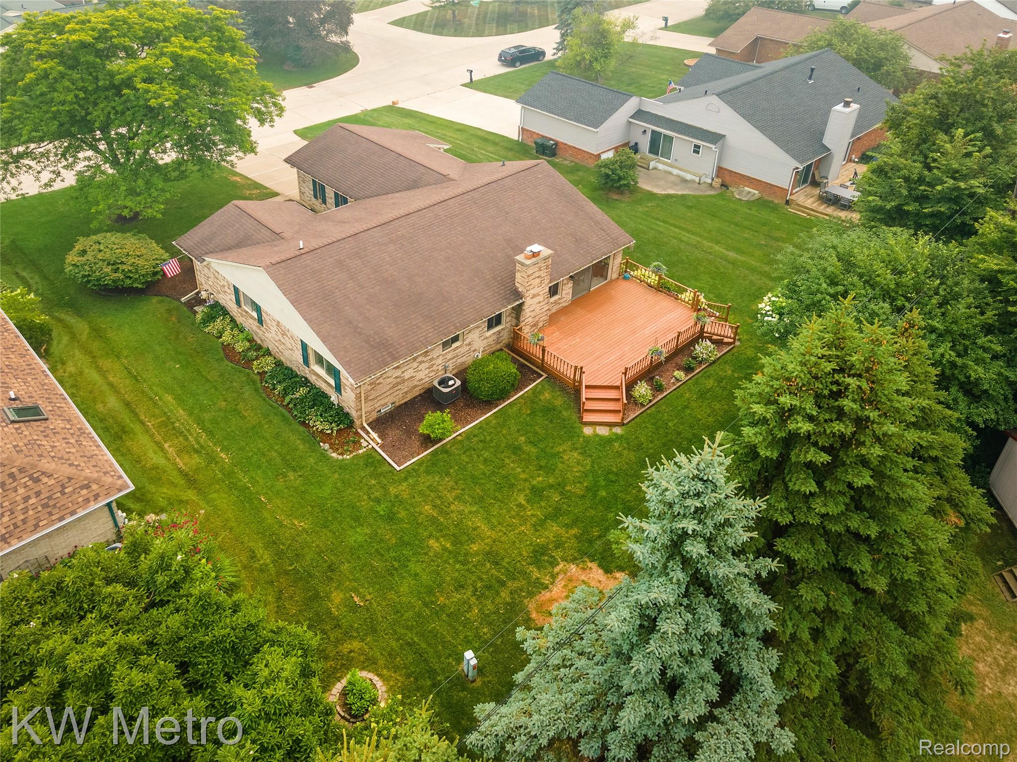 2154 Warrington Road Rochester, MI 48307 - Photo 6 of 41 Rear exterior featuring a spacious wood-finish deck with built-in railing, steps, and surrounding landscaping beds