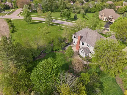 an aerial view of residential house with outdoor space and trees all around