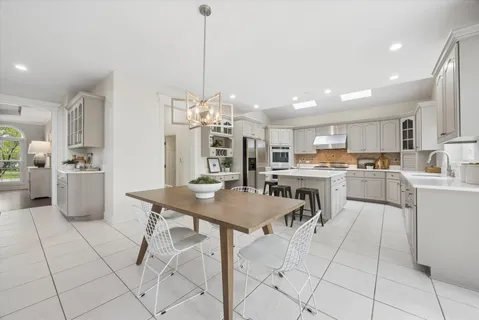 a kitchen with stainless steel appliances kitchen island granite countertop a table chairs and a refrigerator