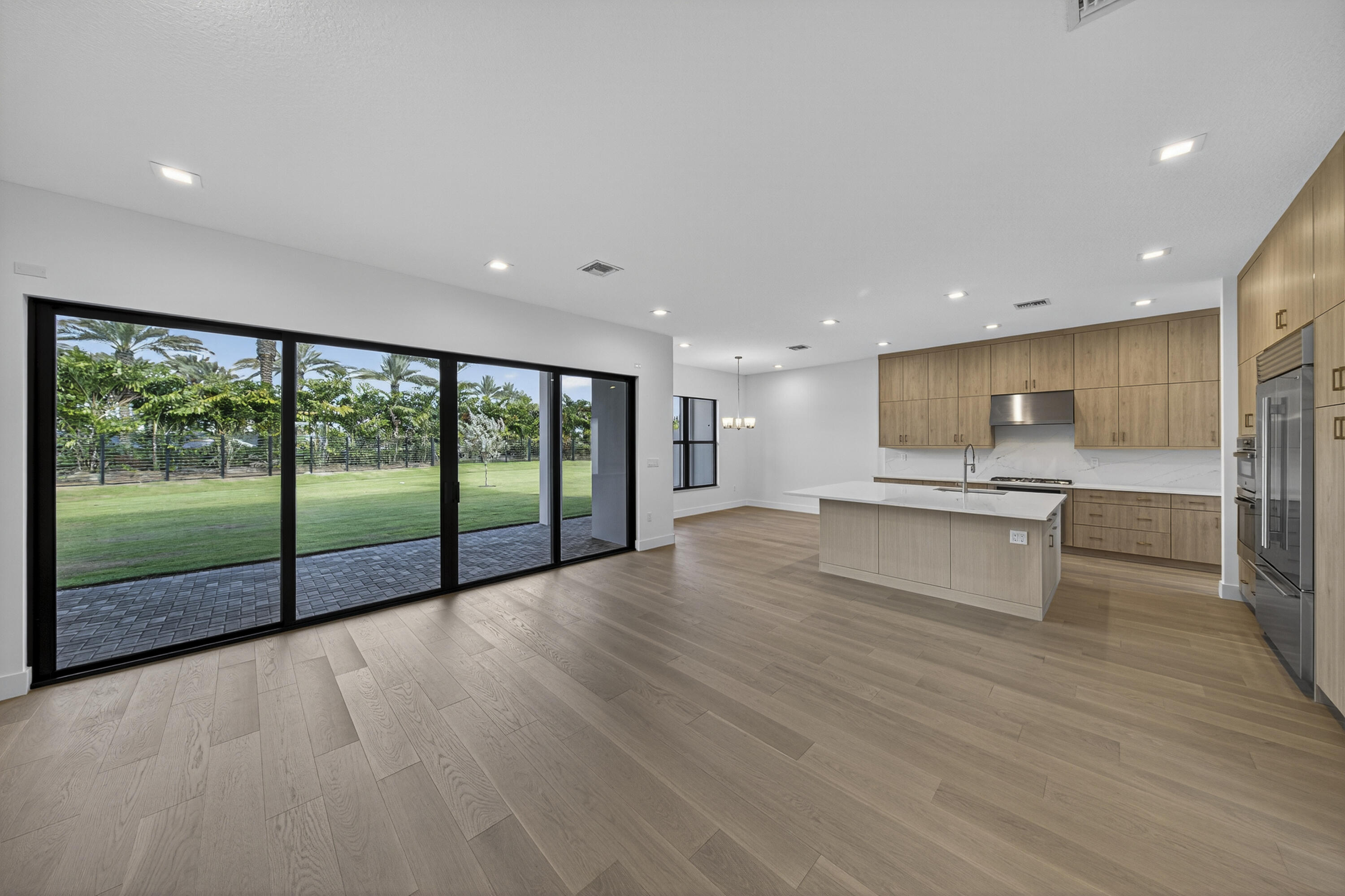 9361 Sunflower Mdw Road Boca Raton, FL 33434 - Photo 12 of 39 a view of an empty room with wooden floor and a kitchen