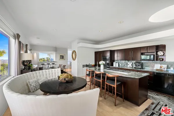 a large white kitchen with a stove a sink a dining table and chairs