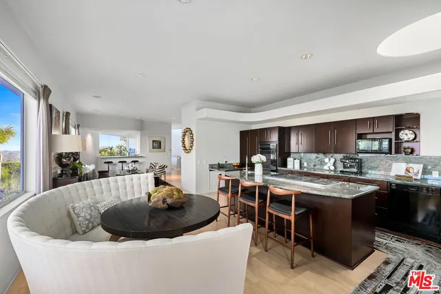 a large white kitchen with a stove a sink a dining table and chairs