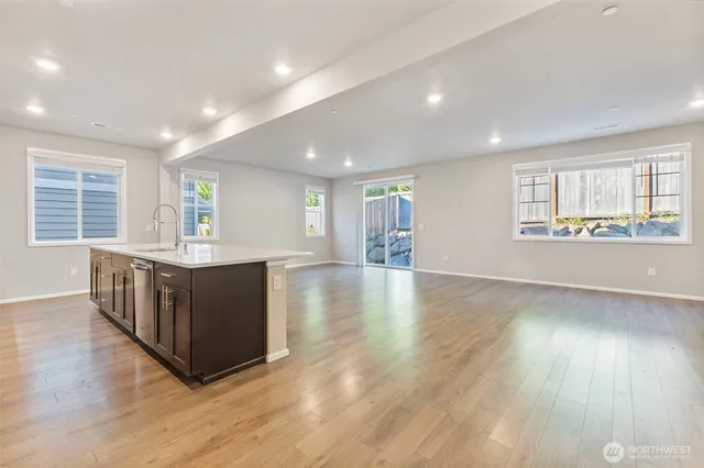 a living room with stainless steel appliances kitchen island hardwood floor and a window