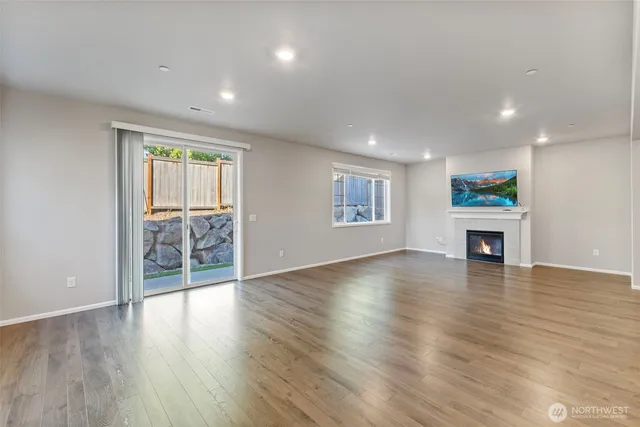 an empty room with wooden floor fireplace and windows