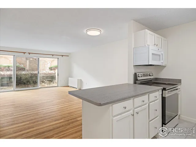 a kitchen with a stove and a white cabinet with granite countertops