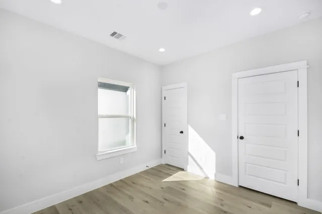 an empty room with wooden floor cabinet and windows