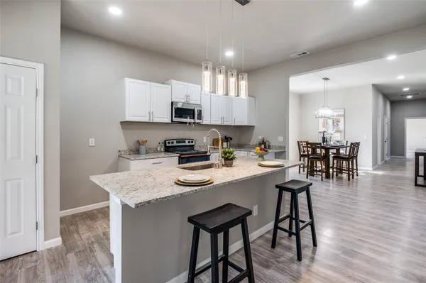 a kitchen with stainless steel appliances granite countertop a table chairs sink and cabinets