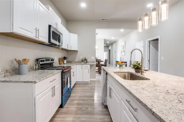 a kitchen with stainless steel appliances granite countertop a sink a stove top oven a counter space and cabinets