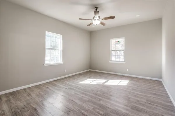 a view of an empty room with a window and wooden floor