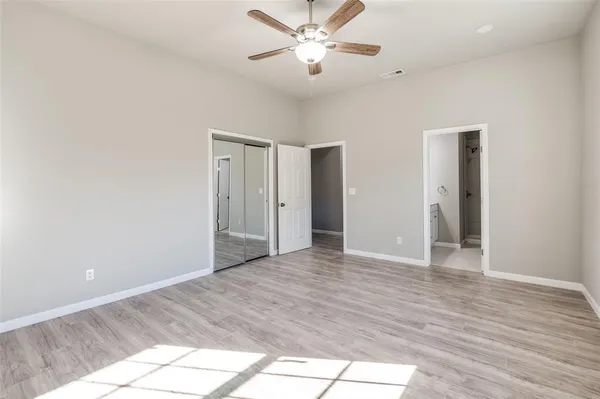a view of an empty room and window a ceiling fan and wooden floor