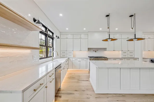 a large kitchen with kitchen island a sink a stove a refrigerator and white cabinets
