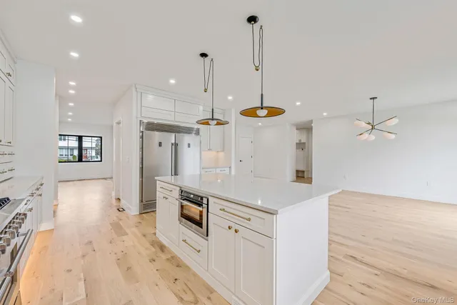 a kitchen with stainless steel appliances kitchen island granite countertop a sink a stove and a wooden floors