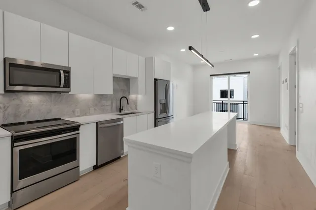 a kitchen with granite countertop a stove top oven a sink dishwasher a refrigerator and a oven with wooden floor