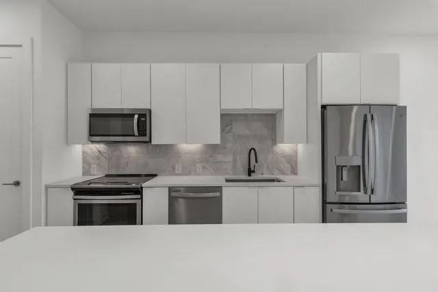 a kitchen with stainless steel appliances a stove a sink and a microwave