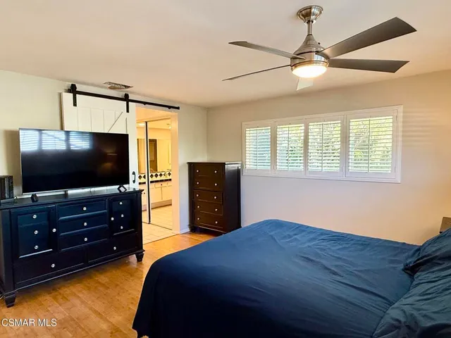 a bedroom with a bed and a flat tv screen on dresser