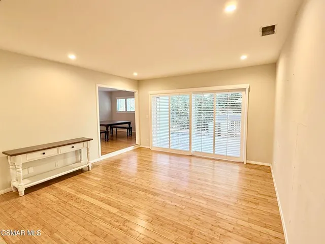 a view of an empty room with a window and wooden floor