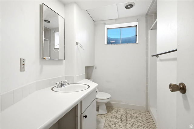 7050 South 260 East Midvale, UT 84047 - Photo 22 of 28 Bathroom featuring a vanity with an integrated sink, patterned tile flooring, a mirrored medicine cabinet, and a window