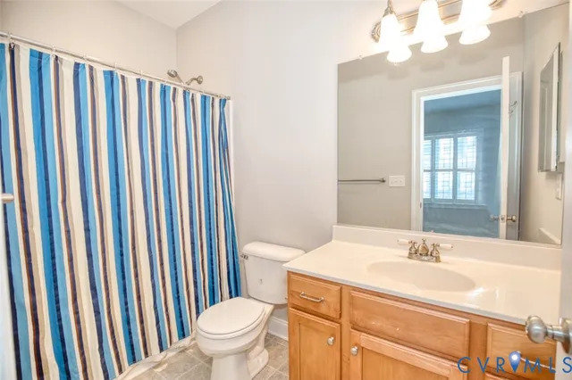 a bathroom with a sink a toilet a mirror and shower curtain