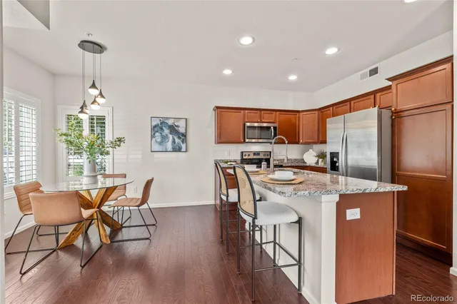 a kitchen with stainless steel appliances granite countertop dining table chairs refrigerator and sink