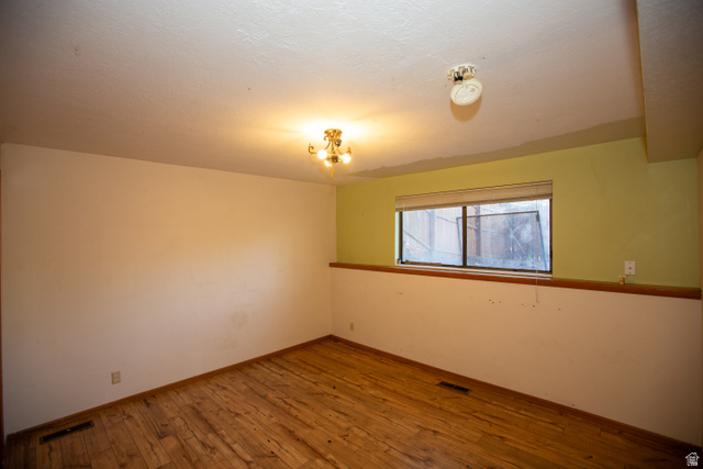1500 Sumac Drive Logan, UT 84321 - Photo 38 of 42 Bedroom with wood-finish flooring, a rectangular window with a window treatment, and a brass-tone chandelier